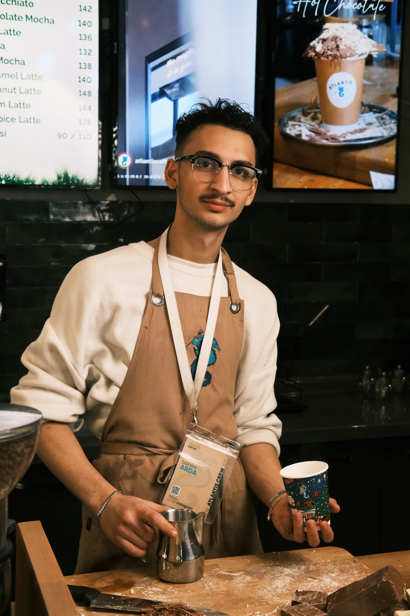 Barista serving drinks at a local café counter